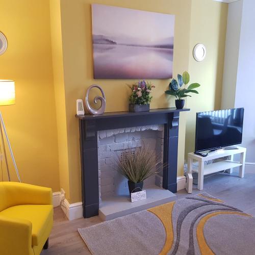 a living room with a fireplace and a tv at Hollis House - 5 Bedroom Contractor Accommodation in Derby in Derby