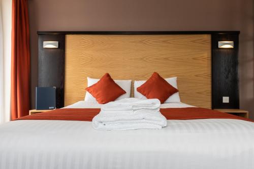 a bedroom with a large white bed with red pillows at Dragonfly Hotel King's Lynn in Kings Lynn