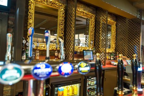 a bar with mirrors on the wall of a bar at Dragonfly Hotel King's Lynn in Kings Lynn