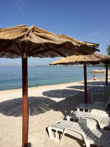 a group of chairs and umbrellas on a beach at Bed & Breakfast Senator in Podstrana