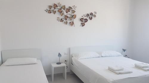 two beds in a white room with a heart decoration on the wall at Kristina Bellavista Rooms in Sarandë