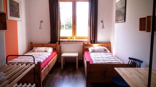 um quarto com duas camas e uma mesa e uma janela em Pokoje Gościnne "Szkoła" em Krasnogruda