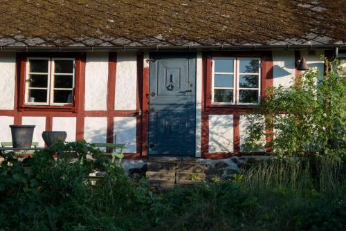 uma casa com uma porta azul e duas janelas em Harrys Hardware Home em Brösarp