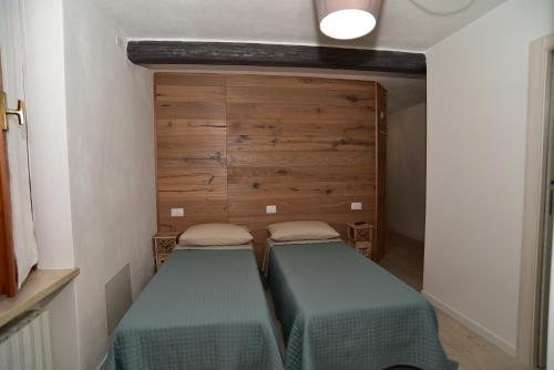2 camas individuais num pequeno quarto com uma parede de madeira em B&B ENANTIO em Belluno Veronese