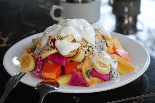 a white plate of food with fruit and ice cream at My Parents Guesthouse in Kampot