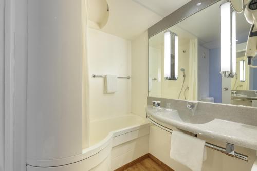 a bathroom with a sink and a tub and a mirror at Mercure Hotel Berlin City West in Berlin