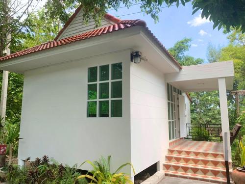 a small white house with a porch at Muaan Resort in Suphan Buri