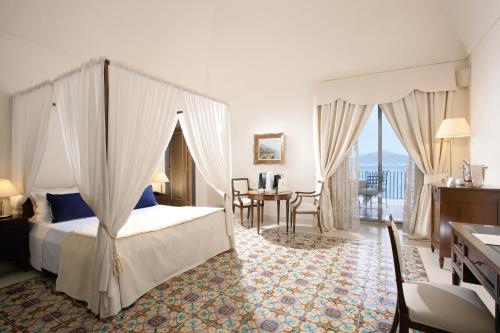 a bedroom with a canopy bed and a table and chairs at Grand Hotel Angiolieri in Vico Equense