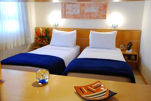 Habitación de hotel con 2 camas y mesa con cristal en Differential Flat, en Belo Horizonte