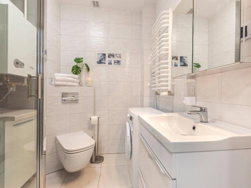 biała łazienka z toaletą i umywalką w obiekcie VacationClub - Pionierów 6, Apartament 25 w mieście Mielno