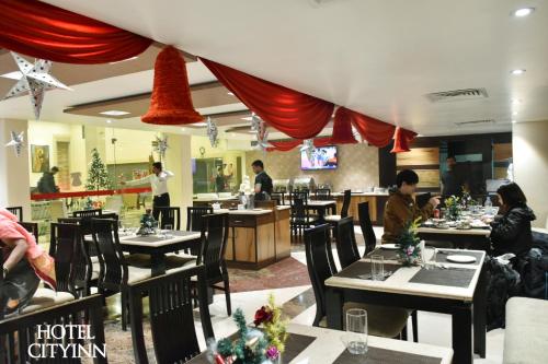 a restaurant with tables and people sitting at them at Hotel City Inn in Varanasi