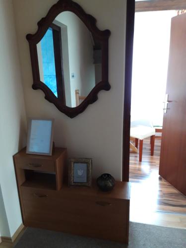 a mirror on a wall next to a dresser with a clock at Studio apartman CENTAR in Ogulin