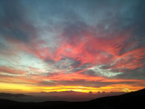 a sunset in the mountains with a cloudy sky at Golden Sea View Suites in Tsakaíoi