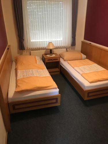 two twin beds in a room with a window at Landhaus Wilhelmshöhe in Uetze