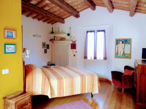 a bedroom with a bed and a chair at la cana dolce in Bertinoro