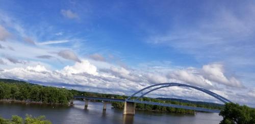 a bridge over a river with a cloudy sky at Trickling Waters Retreat in Marquette