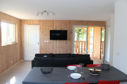a living room with a black couch and a table at Camping les Chênes in Chauzon