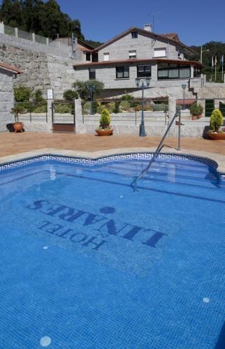 a large blue swimming pool in front of a building at Hotel Liñares in Poio