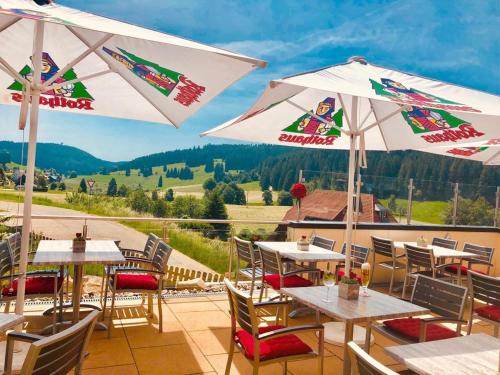 a patio with tables and umbrellas with a view at Hotel Hirschen in Schluchsee