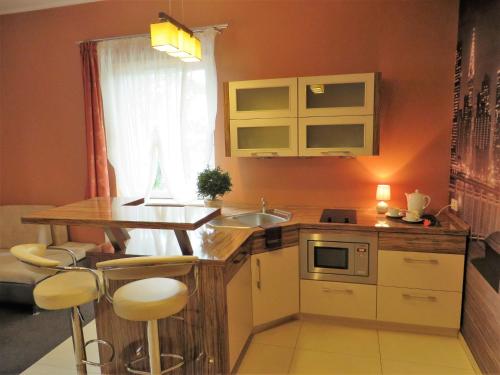 una pequeña cocina con fregadero y encimera con taburetes en City Apartments Protos, en Knurów