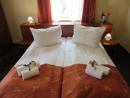 Una cama con dos almohadas blancas y flores. en City Apartments Protos, en Knurów
