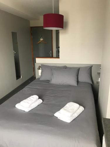 a bed with two white towels on top of it at Smart Appart Caen République in Caen