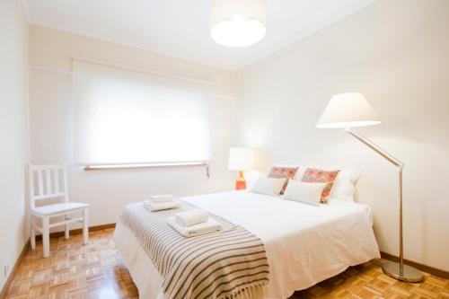 a white bedroom with a bed and a lamp at OHH - Casa da Foz- Near the Beach in Porto
