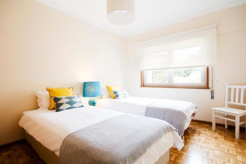 two beds in a small room with a window at OHH - Casa da Foz- Near the Beach in Porto