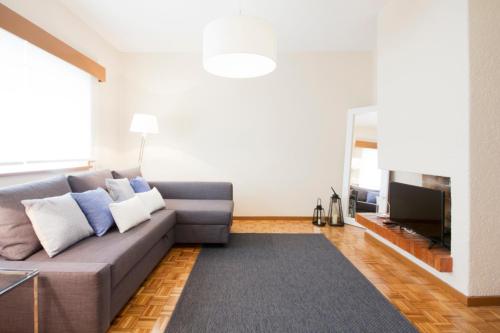 a living room with a gray couch and a television at OHH - Casa da Foz- Near the Beach in Porto