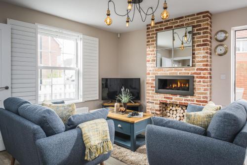 a living room with two blue chairs and a fireplace at Owlers Cottage in Camber