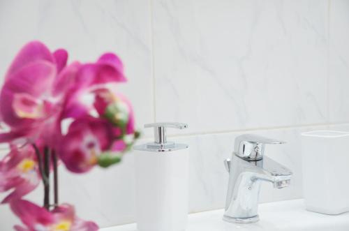 a bathroom with a sink with a vase with purple flowers at Aegle by Heloni Apartments in Athens