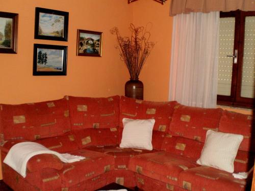 a living room with a red couch with white pillows at Apartamentos Huerta Carúa I y II in Piloña