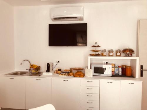 una cucina con armadi bianchi, forno a microonde e TV di Residenza Ca’ Vittoria a Chioggia