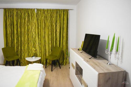 een slaapkamer met een bed en een televisie en groene gordijnen bij Spacious and cozy 3BD+Terrace Couples Apartment in Timişoara