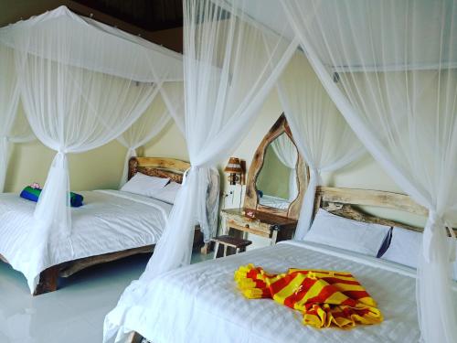 two beds in a room with white drapes at Bamboo Bali Hill Bungalows in Amed