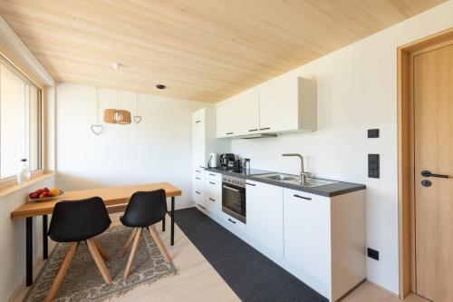 uma cozinha com armários brancos e uma mesa de madeira em Zu Gast bei den Hagspiels em Hittisau