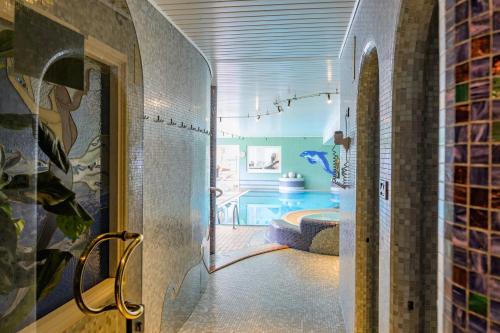 a bathroom with a swimming pool and a room with a tub at Glanzhof Hotel & Apartments in Marlengo