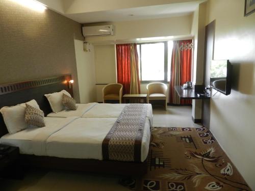 a hotel room with a large bed and a window at Hotel Ayodhya in Kolhapur