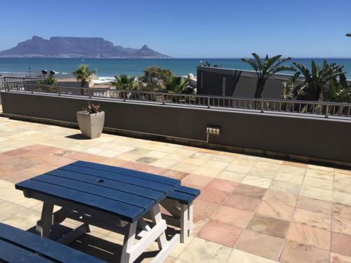a blue picnic table on a patio with the beach at Heaven on Earth - Blouberg Beachfront Self-catering Apartment in Bloubergstrand