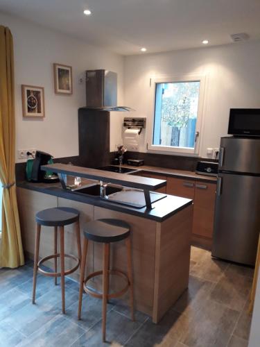 a kitchen with a sink and two bar stools at Le balcon face à l'Aspin in Arreau