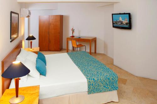 a bedroom with a bed and a desk and a table at Hotel Oceania Cartagena in Cartagena de Indias