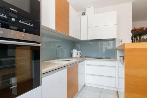 a kitchen with white cabinets and a sink at Dąbrowskiego Apartment in Poznań