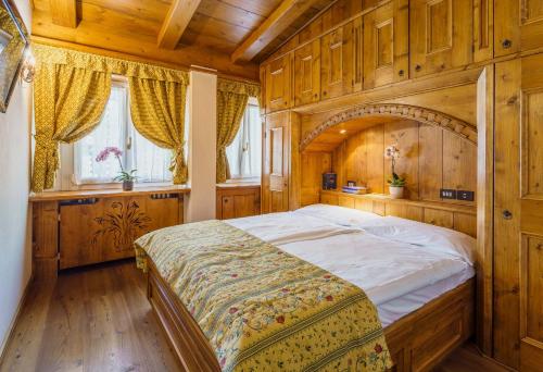 una camera da letto con un grande letto e pareti in legno di Hotel Aquila a Cortina dʼAmpezzo