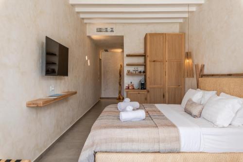 a bedroom with a large bed with towels on it at Panormos Village in Mykonos