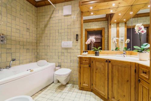 a bathroom with a tub and a toilet and a sink at Hotel Aquila in Cortina dʼAmpezzo