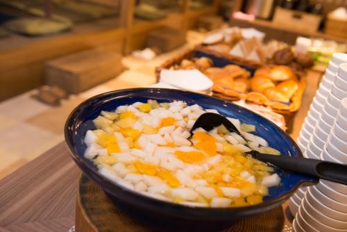 a bowl of food with carrots and onions on a table at Natural Hot Spring SUPER HOTEL Kumamoto Chamber of Commerce in Kumamoto