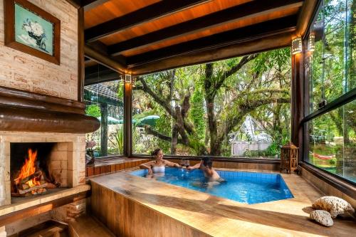 two people in a swimming pool with a fireplace at Pousada Cantos e Contos in Monte Verde