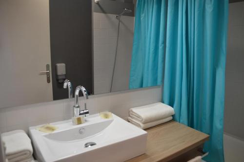 La salle de bains est pourvue d'un lavabo et d'un rideau de douche bleu. dans l'établissement Hôtel des Druides, à Quiberon