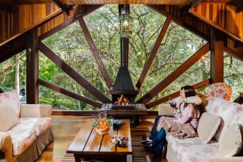 a woman sitting in the living room of a tree house at Pousada Cantos e Contos in Monte Verde