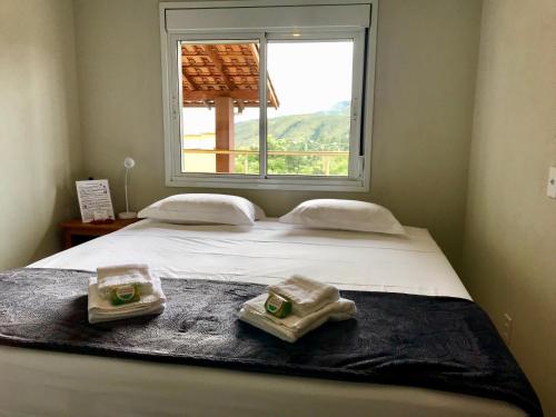 a bed with two towels on it with a window at Vila dos Cristais in Alto Paraíso de Goiás